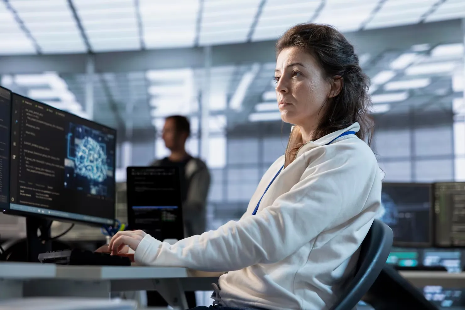 A unosquare technical expert standing in a modern data center holding a laptop, surrounded by illuminated server racks.